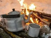 Cowboy Coffee: How to Make Coffee On a Stove Top - kettle brewing over an open campfire with a tin cup
